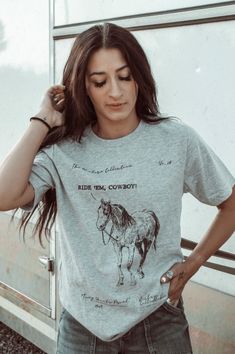 Introducing the Ride 'em Western Collection Graphic Tee - a must-have for any cowboy or cowgirl! Made with high-quality materials and featuring a stunning western design, this tee will keep you comfortable and stylish all day long. Perfect for casual outings or adding a touch of western flair to your wardrobe. 100% Cotton Trendy Relaxed Fit T-shirt For Rodeo, Fitted Graphic Print T-shirt For Rodeo, Western Style Screen Print Tops For Summer, Casual T-shirt For Western-themed Fall Events, Western Style Relaxed Fit T-shirt With Screen Print, Graphic Tee For Rodeo And Spring, Spring Graphic Tee For Rodeo, Spring Rodeo Graphic Tee, Relaxed Fit Western T-shirt For Ranch