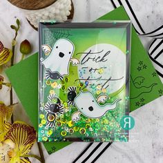 a card with two ghost on it next to some flowers and other things in the background