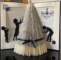 an open book with black and white silhouettes on it that is folded to look like a christmas tree