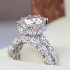 a close up view of a diamond ring on top of a cushioned white surface