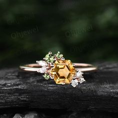 a ring with an orange and white diamond surrounded by green leaves on a piece of wood