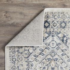 an area rug with blue and white colors on the floor next to a wooden wall