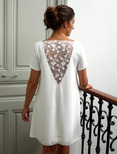 a woman standing on a balcony looking down at the railing with her back to the camera