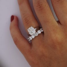 a woman's hand with a diamond ring on top of her finger and the other hand holding an engagement ring