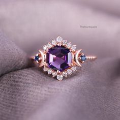 an amethorate and diamond ring sitting on top of a blanket