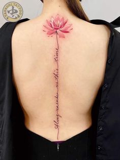 the back of a woman's neck with a pink lotus tattoo on her lower back