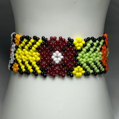 a white mannequin torso wearing a multi colored beaded bracelet on it's chest