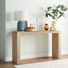 a wooden table with vases and pictures on it next to a white rug in a room