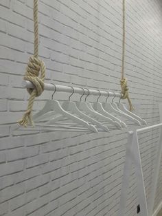 several white clothes hangers with rope attached to them against a brick wall in an office building