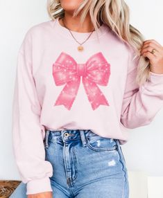 This Pink Sparkle bow sweatshirt exudes a cozy and stylish vibe, perfect for the colder months. The ribbed knit collar and classic fit offer comfort and durability. Ideal for those who love a touch of sparkle in their wardrobe, this sweatshirt is a must-have for holiday gatherings and festive celebrations. Product features - Made with a medium-heavy fabric blend of 50% cotton and 50% polyester for coziness - Ribbed knit collar with seam for elasticity and shape retention - Ethically grown US cot Casual Long Sleeve Sweater With Bow, Casual Long Sleeve Bow Sweater, Pink Bow Top For Fall, Trendy Fall Top With Bow, Cute Winter Sweatshirt For Gift, Cute Winter Sweatshirt Gift, Casual Long Sleeve Tops With Bow, Fall Cotton Top With Bow Detail, Pink Tops As Winter Gifts