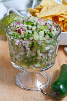 a glass bowl filled with chopped vegetables on top of a wooden table