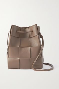 "It almost becomes a blank canvas for the various processes and for playing around with colors, styles, sizes and construction techniques," says Bottega Veneta of its iconic intrecciato. Assembled in a boxy shape with drawstring ties, this 'Cassette' bucket bag is expertly crafted from soft leather. Use the dust cover between wears or fill it with rolled tees to maintain the shape even longer. Designer Square Leather Bucket Bag, Luxury Beige Bucket Bag With Intrecciato Weave, Designer Rectangular Bucket Bag With Intrecciato Weave, Arm Candies, Funky Bags, Bottega Veneta Cassette, Small Buckets, Fashion Basics, Bottega Veneta Bags