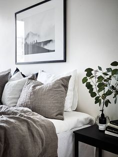 a bed with white sheets and gray pillows