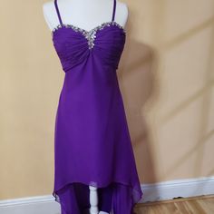 a purple dress is displayed on a mannequin head stand in front of a wall