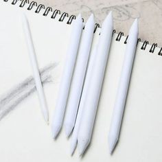 three white pens sitting on top of a notebook