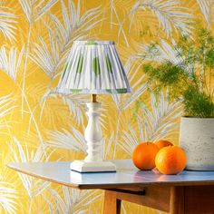 an orange sitting on top of a table next to a lamp and potted plant