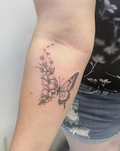 a woman's arm with a butterfly and flowers tattoo on the left side of her arm