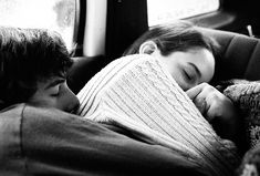 two children sleeping on the back of a car seat with their arms around each other