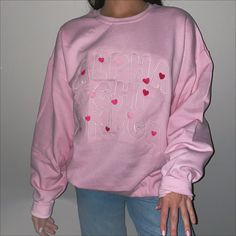 a girl wearing a pink sweatshirt with hearts on it