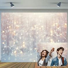 two people standing next to each other in front of a wall with snowflakes on it