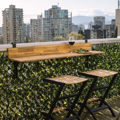 two wooden tables sitting next to each other on top of a balcony with tall buildings in the background