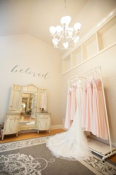 a bride's wedding dress hangs in front of a chandelier with the word beloved written on it