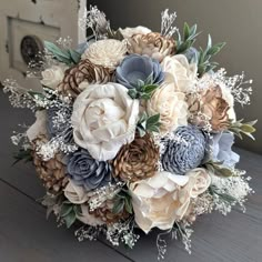 a bridal bouquet with blue and white flowers on a wooden table in front of a door