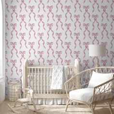 a baby's room with a crib and wallpaper that has pink bows on it