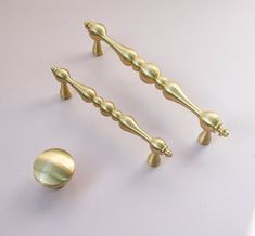 two golden handles and knobs on a white surface