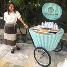 a woman standing next to a cart filled with lots of bottles and soaps on wheels