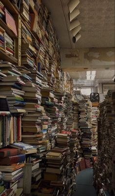 a room filled with lots of books next to a wall covered in stacks of books