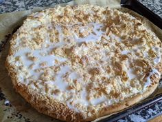 an uncooked pizza sitting on top of a pan covered in white sauce and crumbs