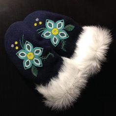 a blue hat with white fur and flowers on the front, sitting on a black surface