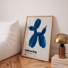 a blue balloon dog poster sitting on top of a wooden floor next to a lamp