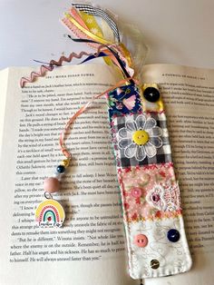 an open book with buttons and beads attached to it, sitting on top of a table