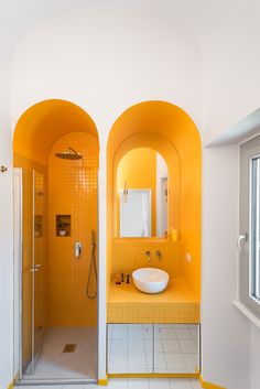 a bathroom with yellow walls and tiled flooring next to a sink, shower and window