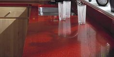 a kitchen counter top with two glasses on it and an alarm clock in the background