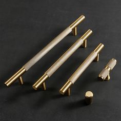 four brass handles and knobs on a black surface