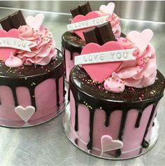 two cakes decorated with chocolate and pink frosting, one has hearts on top that say i love you