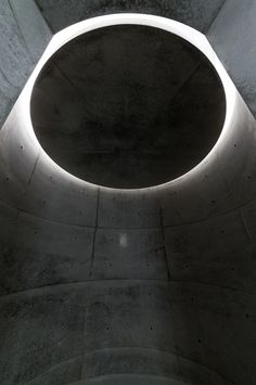 a circular light fixture in the center of a concrete structure with cement walls and flooring