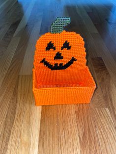 an orange plastic pumpkin sitting on top of a wooden floor