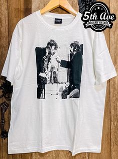 a white t - shirt with an image of two men talking to each other on it