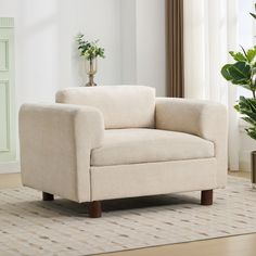 a white chair sitting on top of a wooden floor next to a potted plant