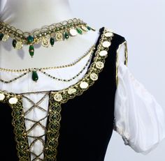 a woman's black and white dress with gold chains, green beads and coins on it