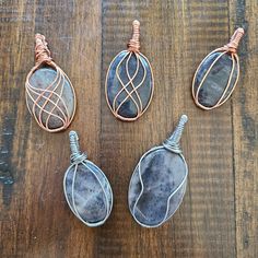 three wire wrapped stone pendants sitting on top of a wooden table next to each other