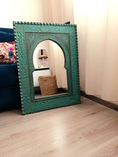 a mirror sitting on top of a wooden floor next to a blue couch and lamp