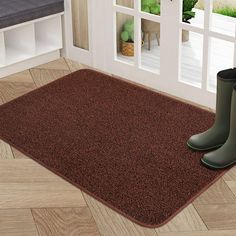 a pair of rain boots sitting on top of a brown rug in front of a door