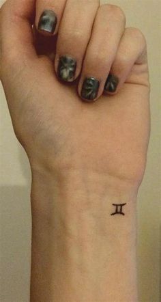 a woman's wrist with a small pi symbol tattoo on her left arm and the word