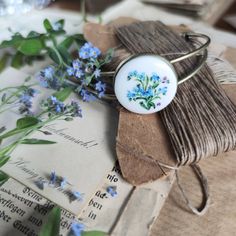 An original bracelet with a hand-painted cabochon from  porcelain!The flowers pattern was painted by hand on a porcelain cabochon, special paints and then fired at the right temperature. The drawing is very small, each element is painted under the microscope, miniature painting.The ring is in a romantic style. The bracelet is very elegant. Cabochon is made of Chinese porcelain and bound in a brass base in gold. diameter of a porcelain cabochon - 2,5 cm ( 1")diameter: 6.5 x 5.5 cm ( 2.6 x 2.2")No Dainty Enamel Jewelry Gift, Enamel Bracelet Jewelry Gift, Handmade Enamel Flower Jewelry, Handmade Dainty Enamel Jewelry, Vintage Handmade Flower Jewelry, Hand Painted Enamel Jewelry Gift, Dainty Handmade Enamel Jewelry, Hand Painted Enamel Jewelry For Gifts, Vintage Handmade Floral Jewelry