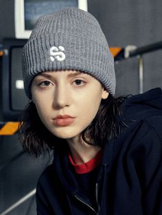 a young woman wearing a beanie and looking at the camera